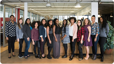 Diverse group of women posing for a team photo in an office.